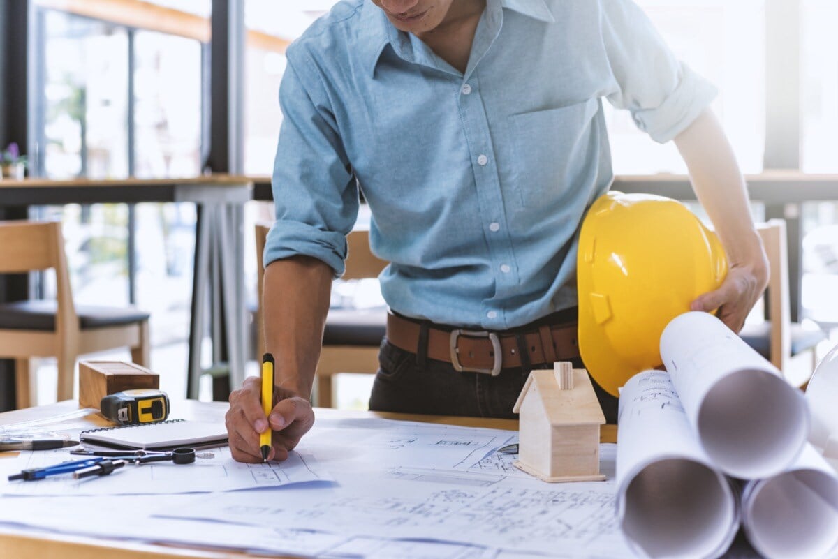 Close up of civil engineer working on blueprint at construction site; construction project documents lessons concept.