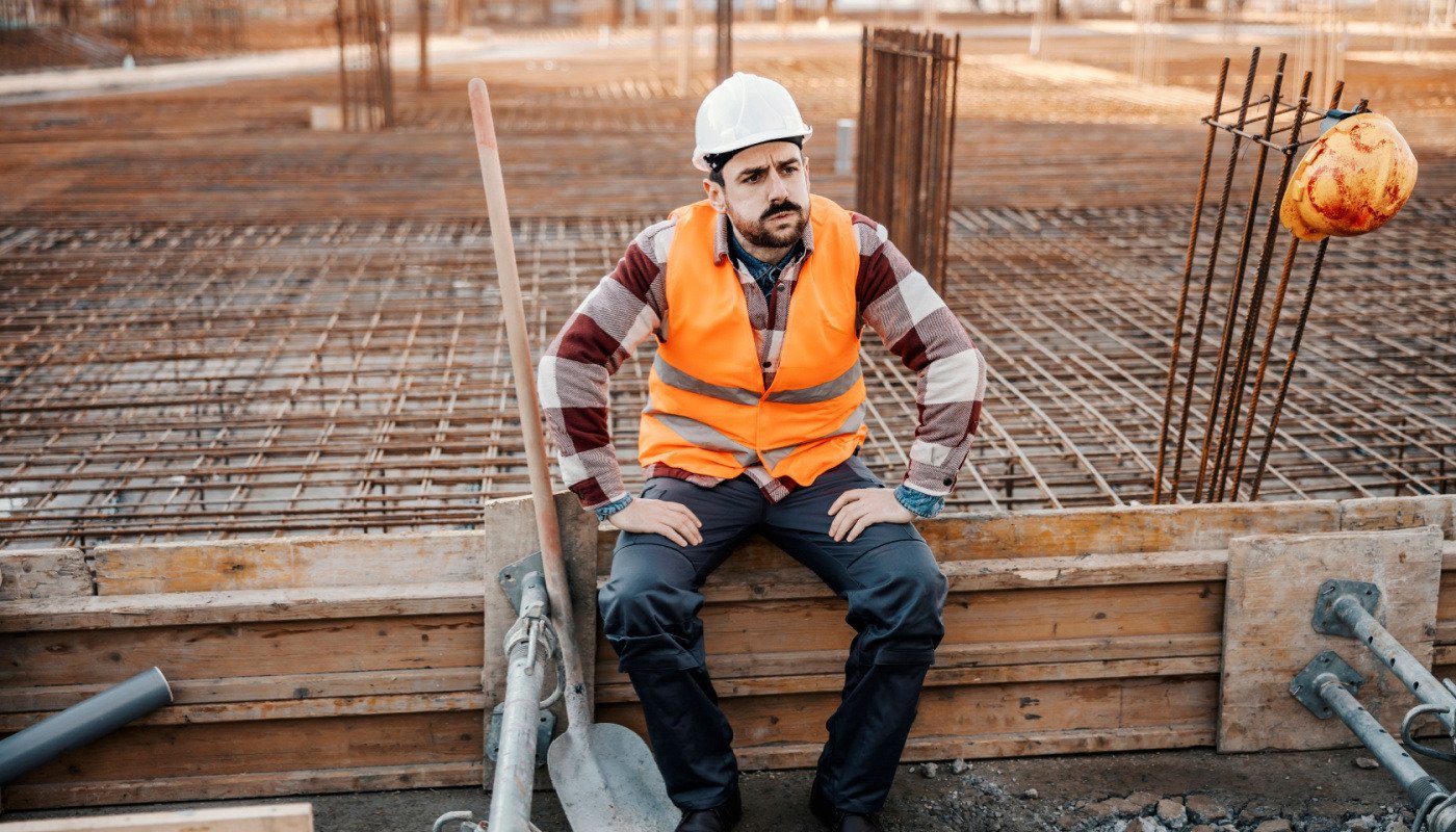 Exhausted construction site worker; construction delays concept
