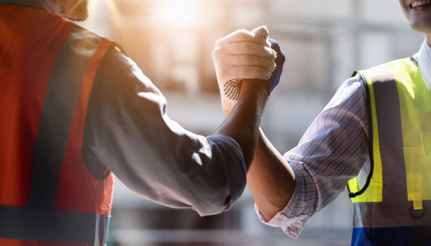 Workers clasping hands signifying teamwork and determination to succeed; mental health in construction concept