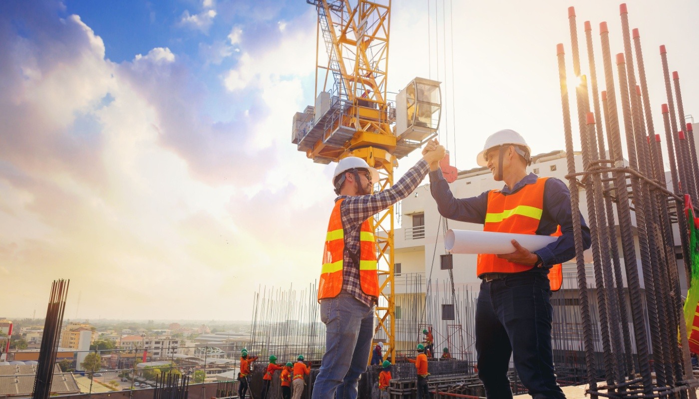 Architect and engineer construction worker shaking hands, working at outdoor construction site; starting construction business concept