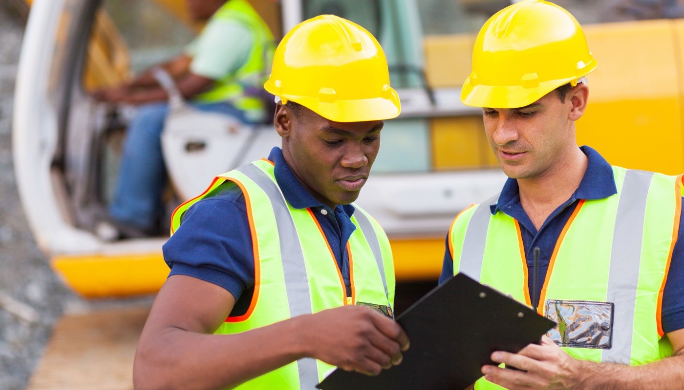 Workers in yellow hard hats on construction site; budget overruns concept
