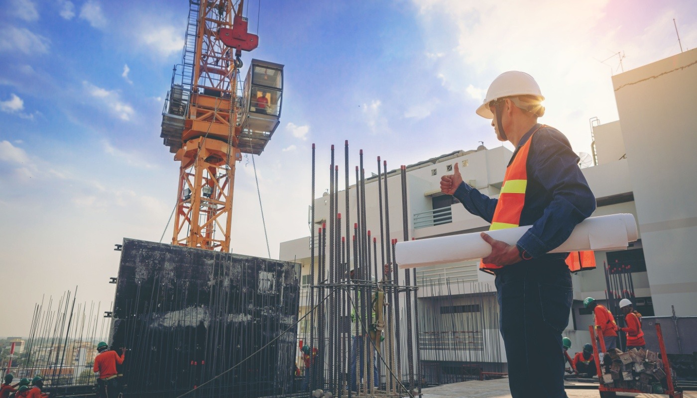 Engineer inspecting building site with blueprints; construction leadership concept