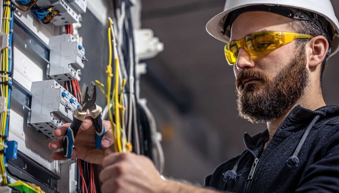 Electrician works on a switchboard with an electrical connecting cable; AI electrical construction concept