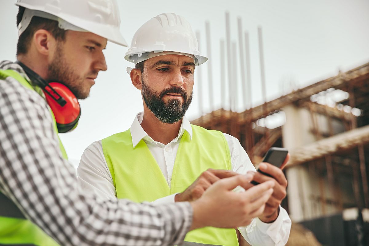 Architects in hard hats using mobile app; usability in construction management software concept