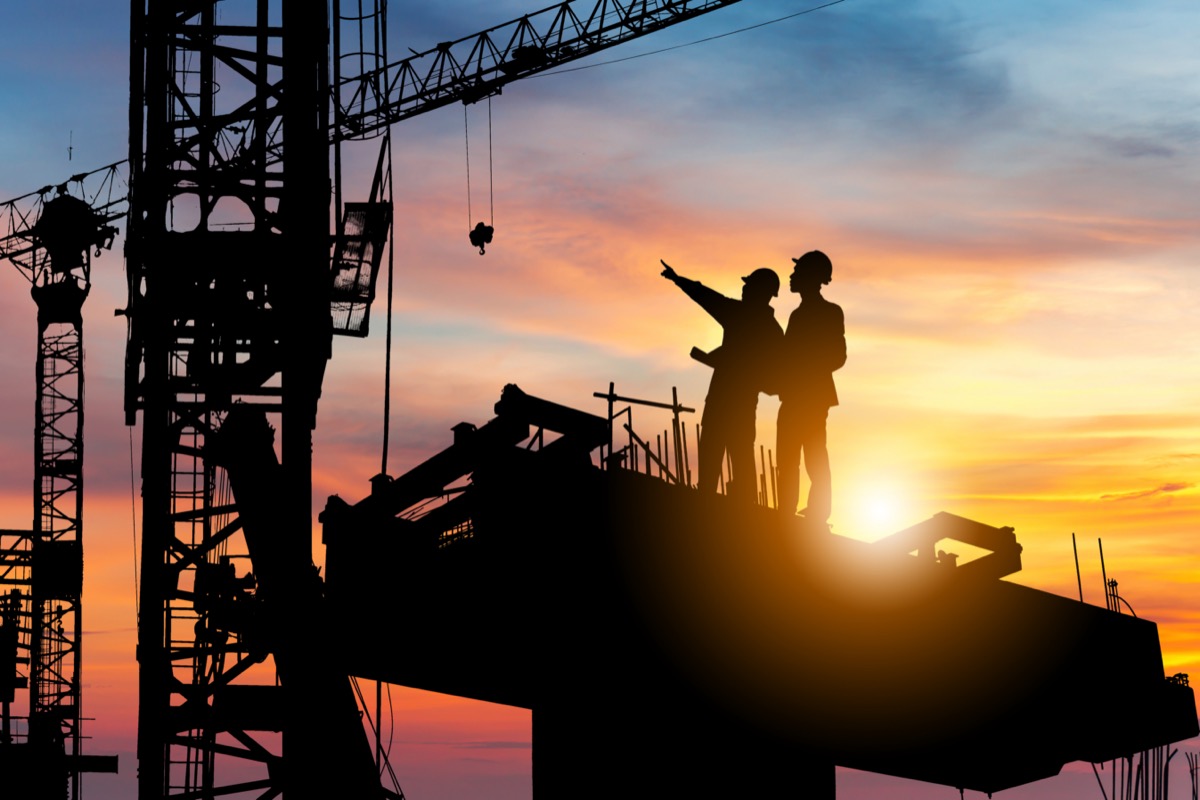 Silhouette of construction workers at building site; simple construction software concept