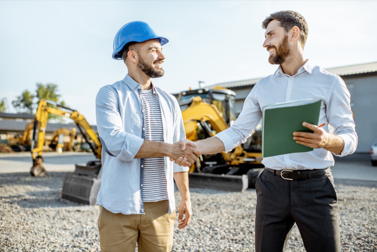 Builder shaking hands with heavy machinery sales consultant; protect your cash flow concept