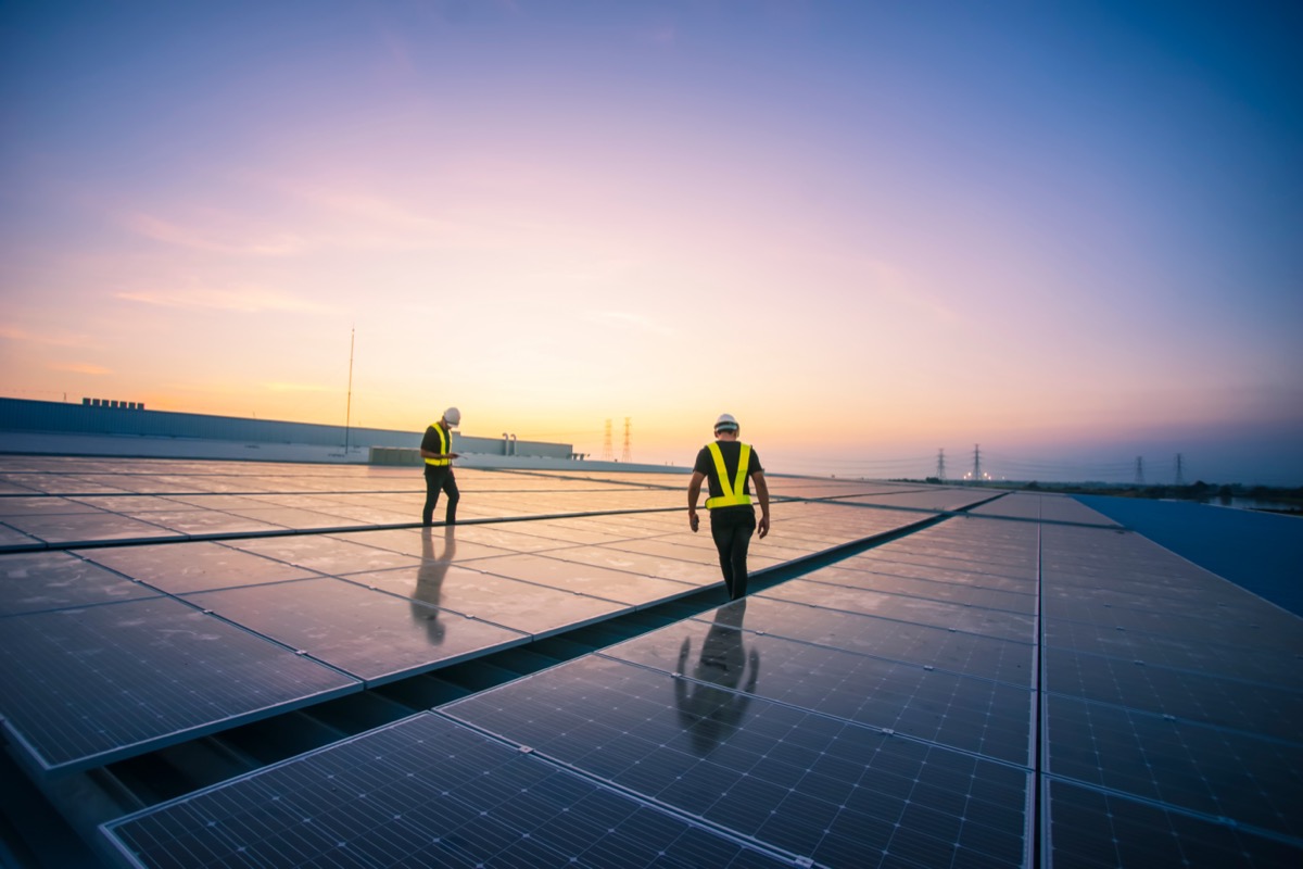 Engineer checking installation of solar cells on the roof of factory; securing financing concept