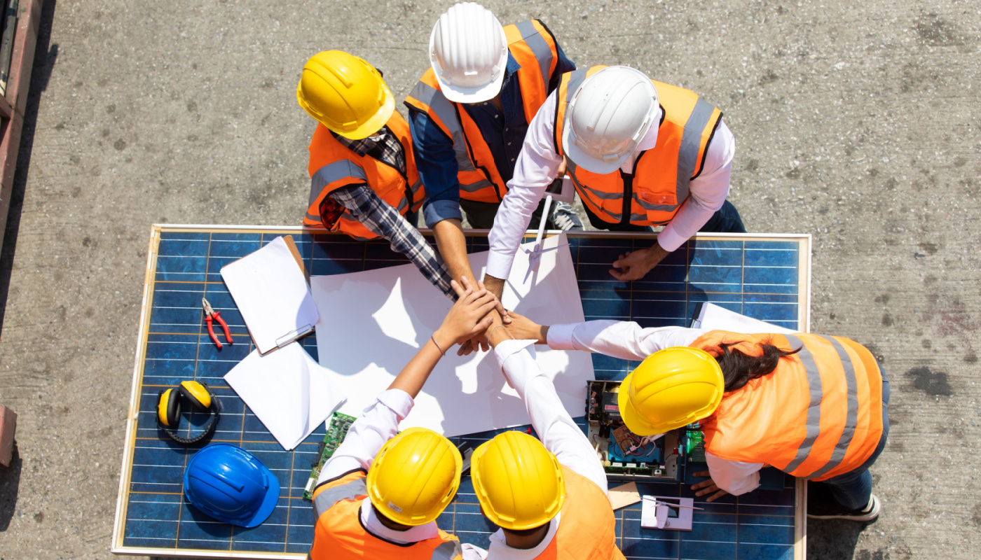 Group of construction workers and engineers on site, working together; 