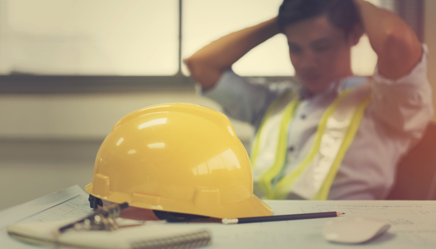 Engineer holding head in hands; project documentation mental toll concept