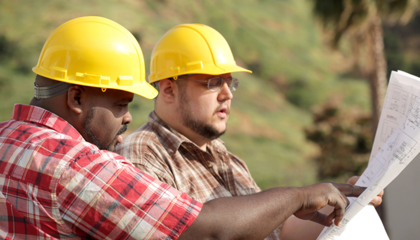 Construction workers looking at plan on site; project risk concept