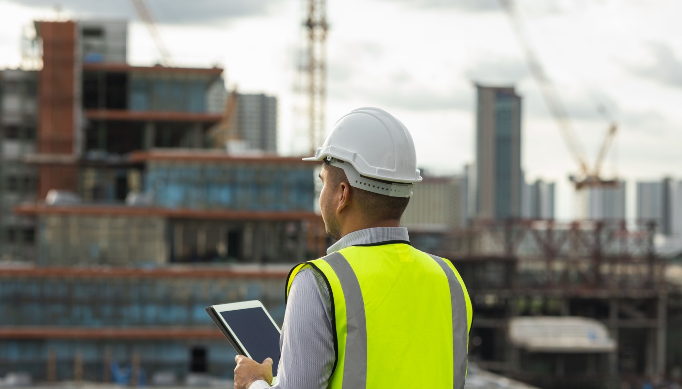 Engineer in hardhat on rooftop using tablet; improve project outcomes concept