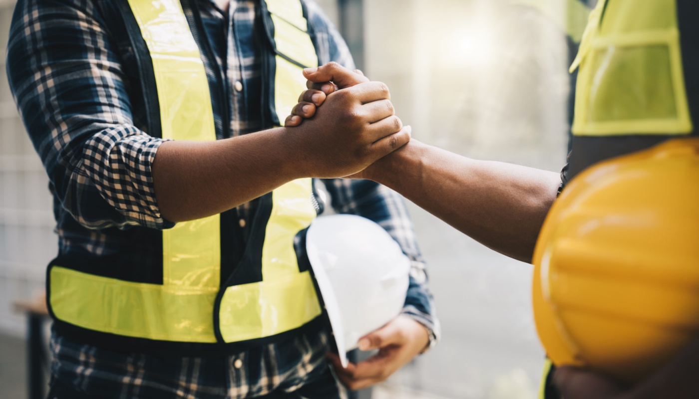 Construction workers shaking hands; reduce project risks concept