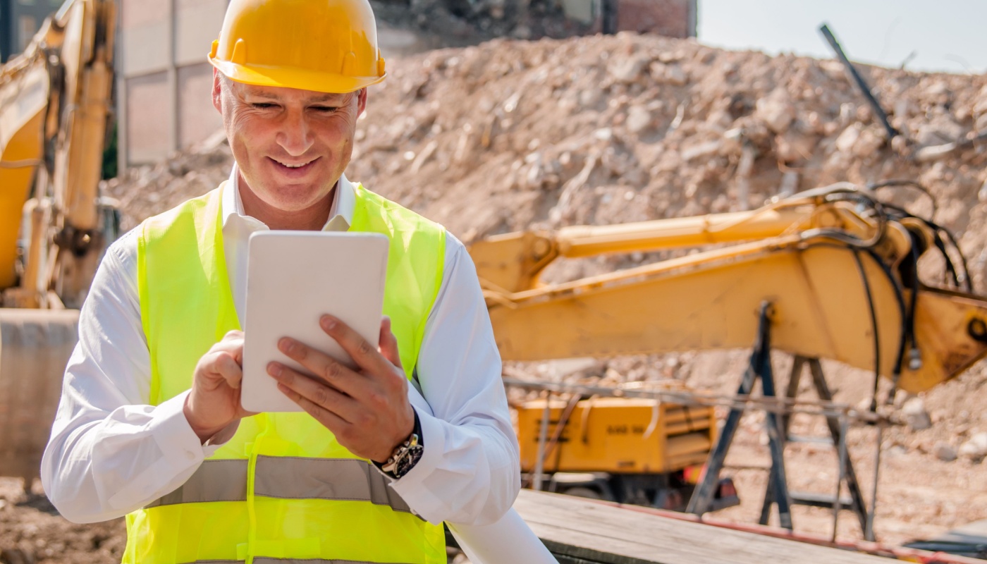 Construction manager at building site using digital tablet; manage construction projects concept