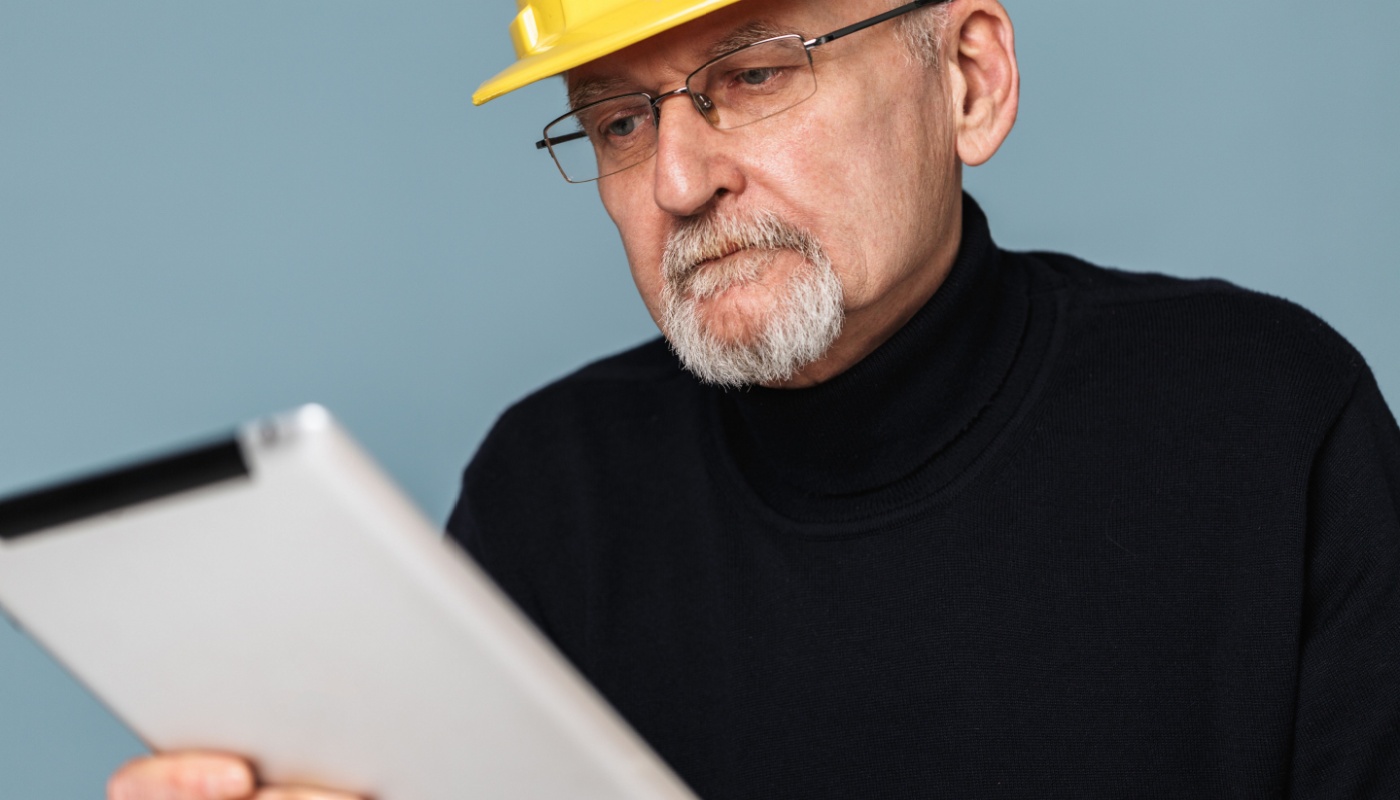 Contractor in yellow hard hat using tablet; tech resistance concept