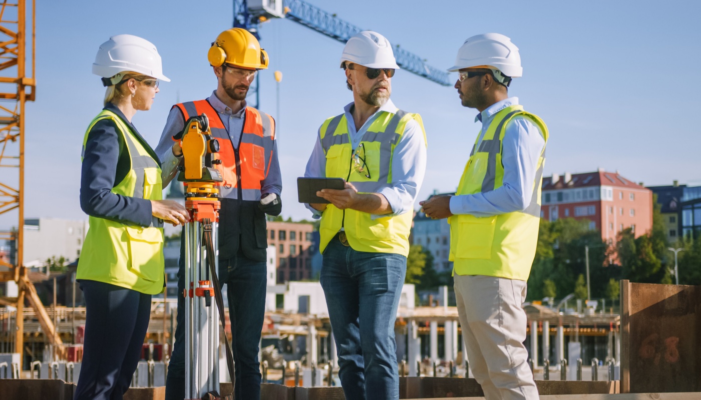 Team of specialists use tablet on construction site; construction management software concept