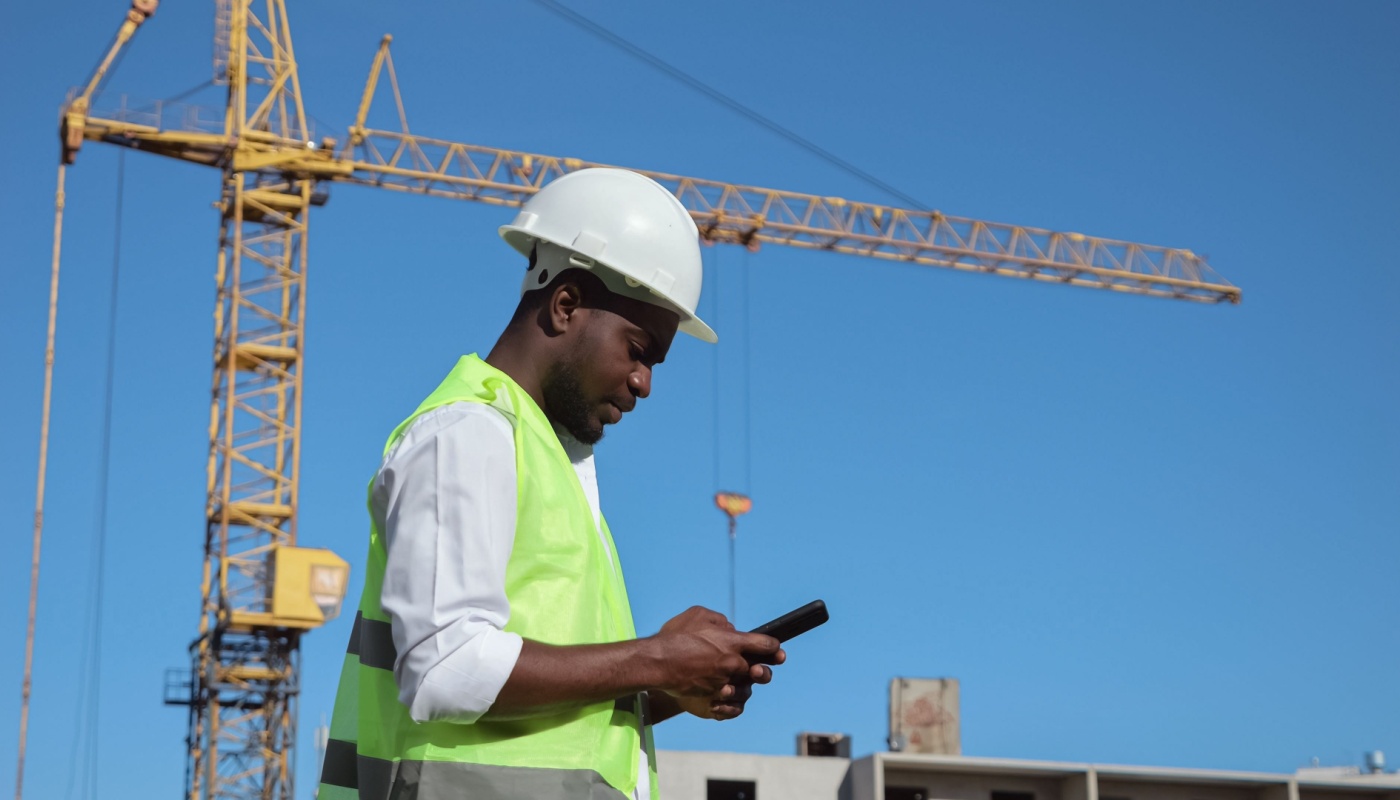 Construction worker on site using smartphone; construction daily reports concept