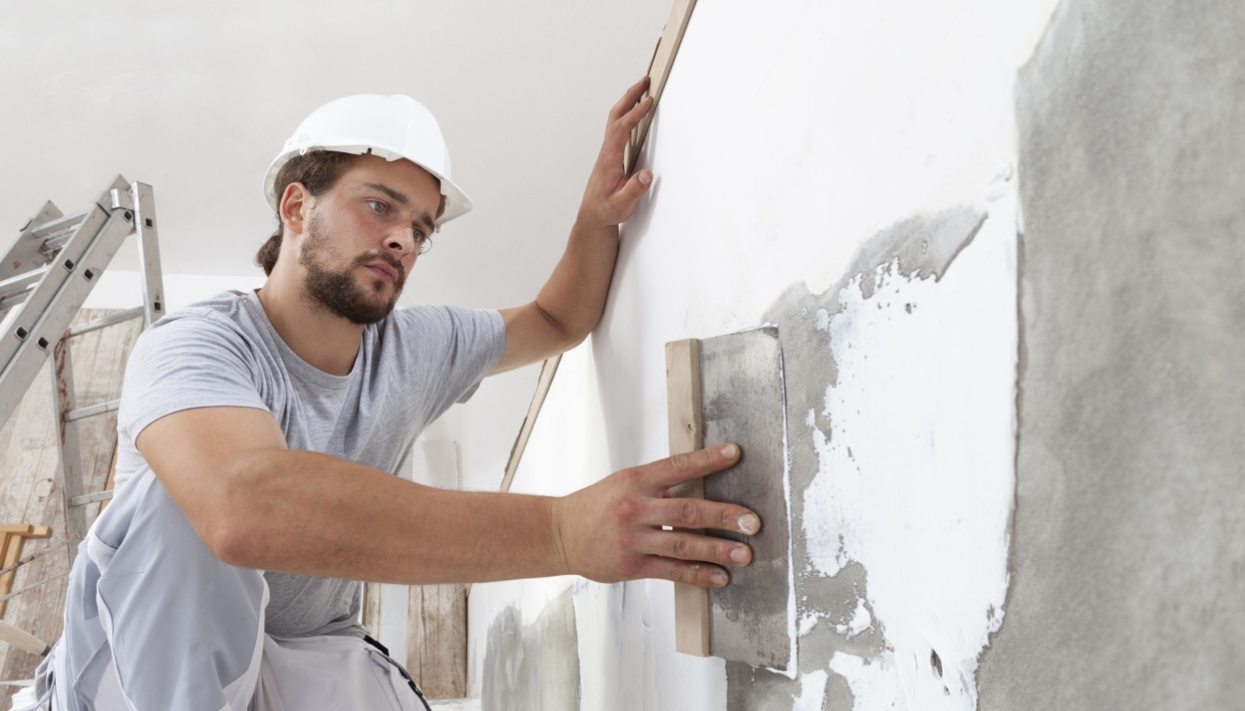 Trades worker at work with trowel, plastering a wall; business resilience concept