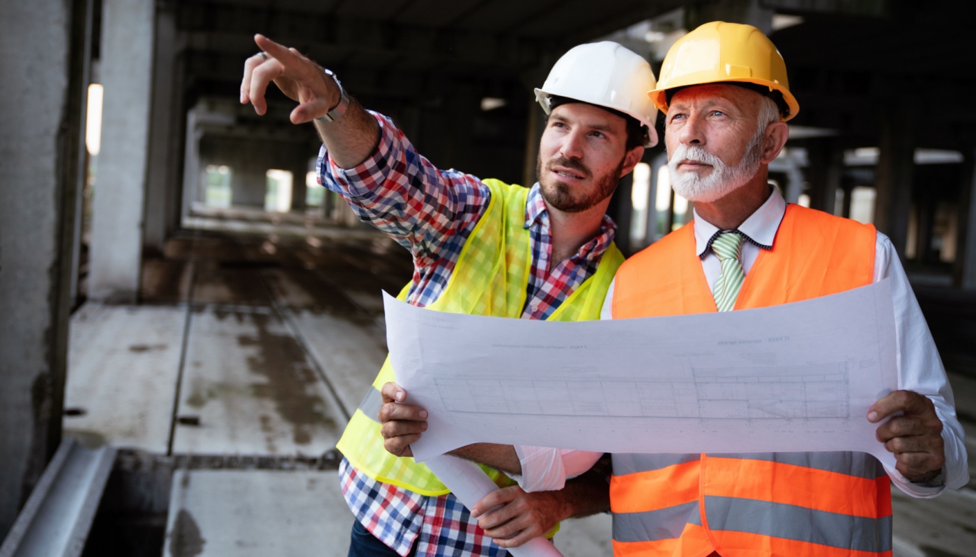 Architect and engineer working together on construction site; different generations at work concept