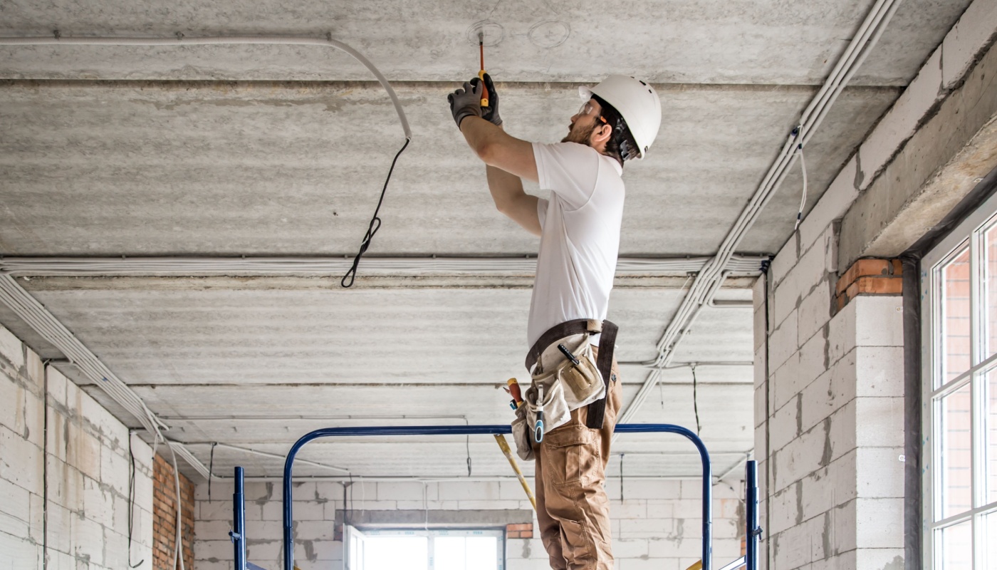 Electrician with a tool in his hands, working with cable on the construction site; NECA 2024 concept