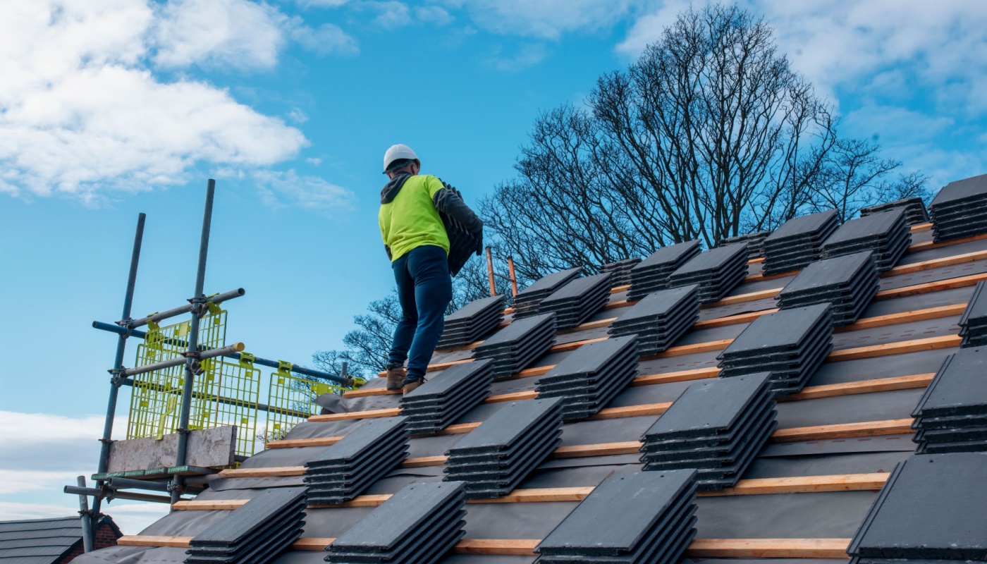 Construction worker installing roof tiles; supply chain software solutions concept